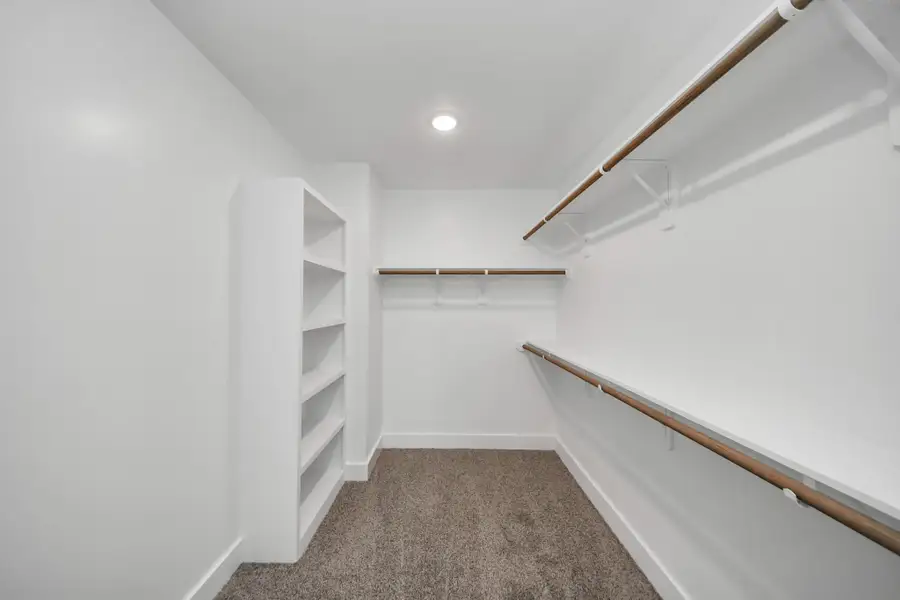 Primary Walk-In Closet – Spacious walk-in closet with built-in shelving, abundant hanging space, and organized storage.