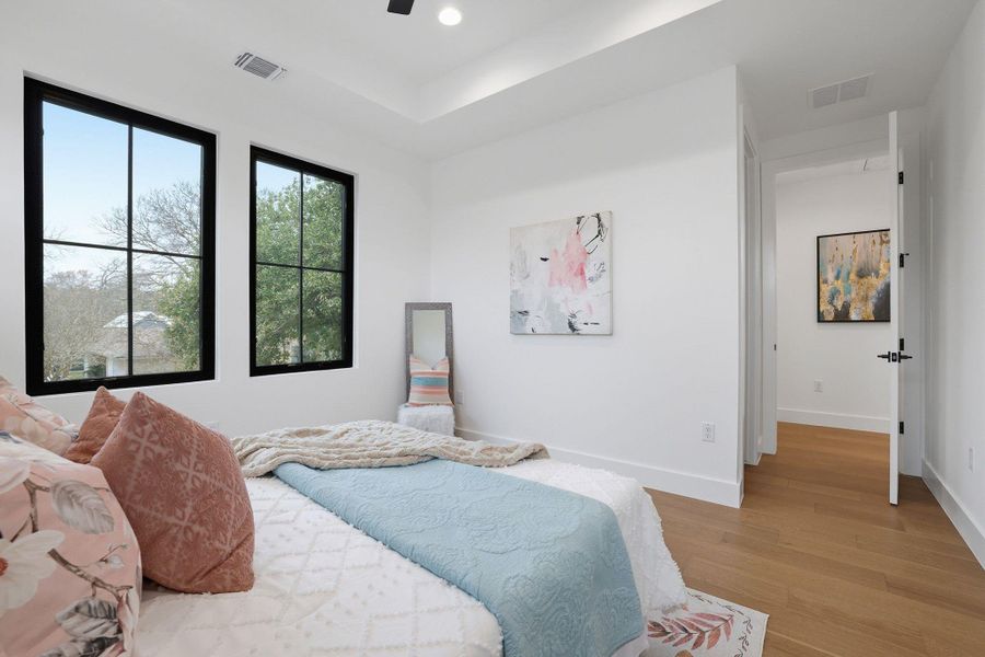 Bedroom featuring light wood-style flooring, ceiling fan, recessed lighting, and a tray ceiling