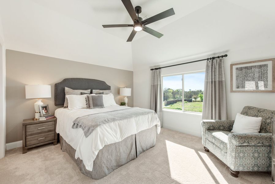 Bedroom with king bed, vaulted ceiling, ceiling fan, and large window with gray curtains