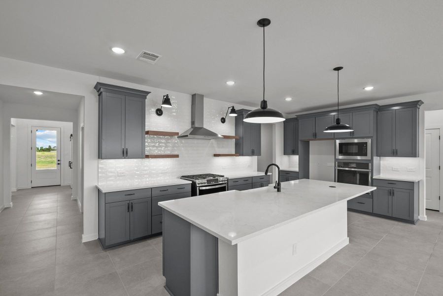 Gourmet kitchen with grey cabinets and quartz countertops