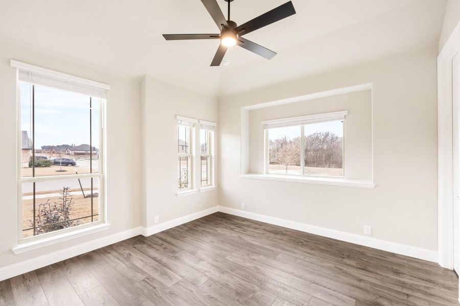Empty bedroom with hardwood floors, ceiling fan, and multiple windows with natural light Empty bedroom with hardwood floors, ceiling fan, and multiple windows with natural light