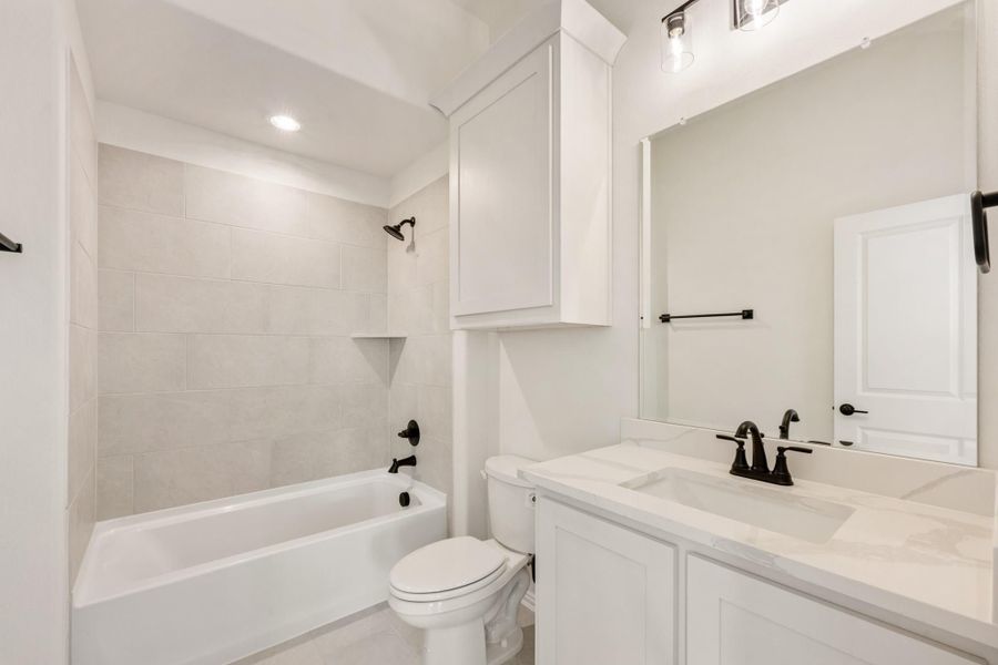 Full bathroom with white vanity, tub-shower combo, and dark bronze fixtures