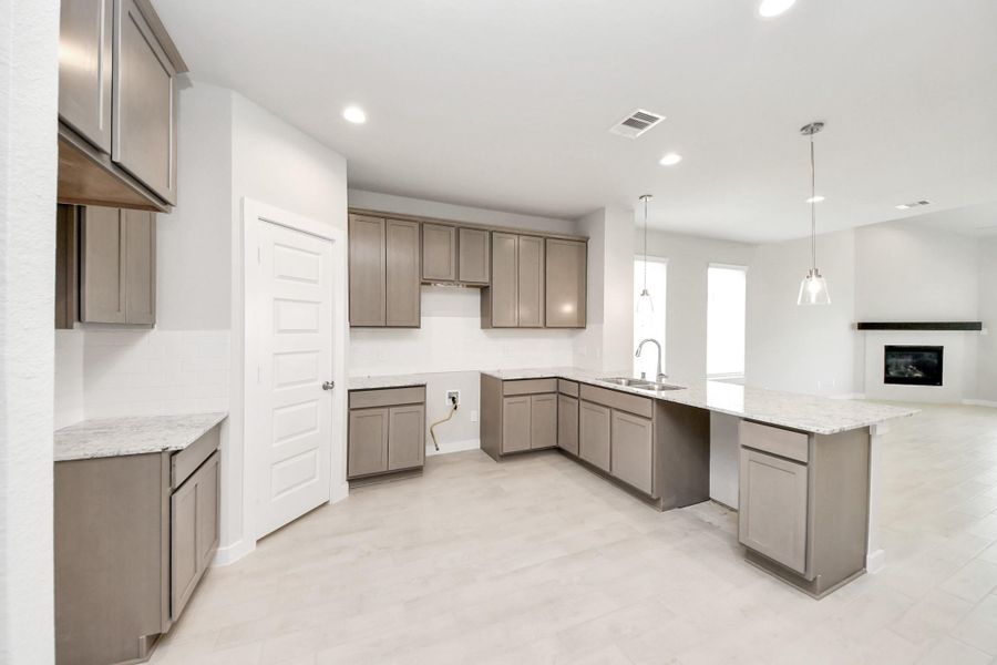 The kitchen is a culinary haven, featuring granite countertops, a tile backsplash, stainless steel appliances, and 42” upper cabinets. Sample photo of completed home with similar floor plan. Actual colors and selections may vary.