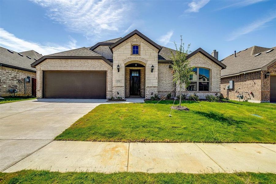 French country home featuring a garage and a front yard