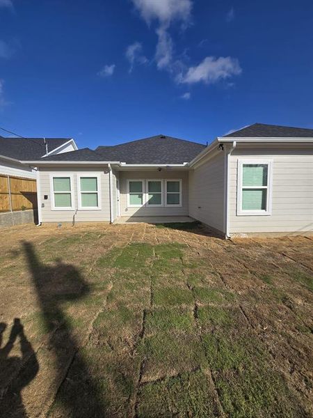 Rear view of property featuring a patio area and roof with shingles