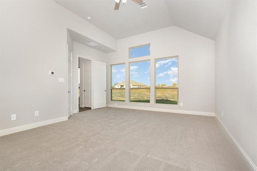 Empty room with light carpet, a ceiling fan, and lofted ceiling