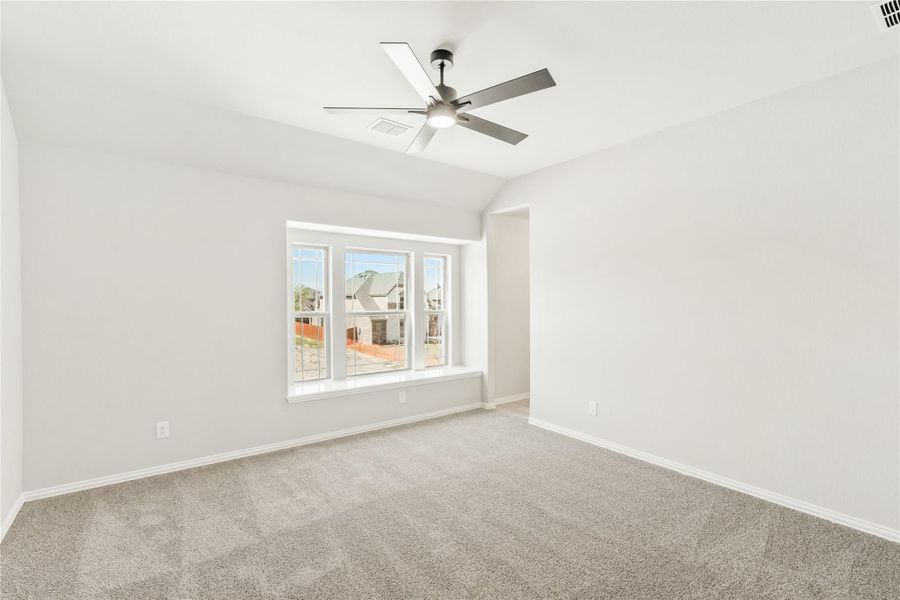 Empty bedroom with carpet, ceiling fan, vaulted ceiling, and large triple window Empty bedroom with carpet, ceiling fan, vaulted ceiling, and large triple window