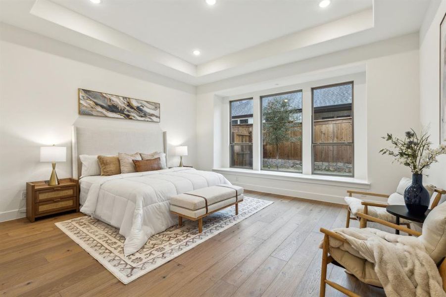 Bedroom with a raised ceiling and light wood-type flooring