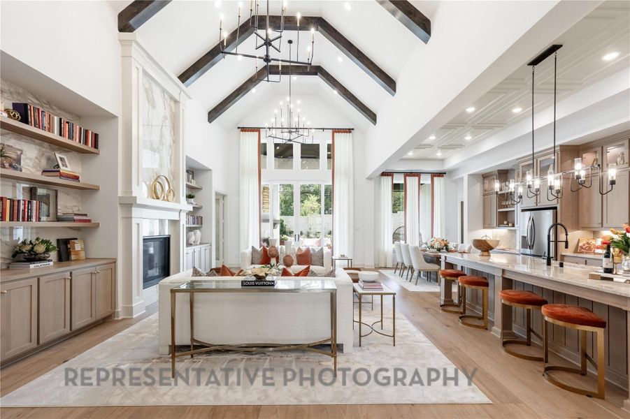 Living area with a fireplace, high vaulted ceiling, light wood-style flooring, and an inviting chandelier Living area with a fireplace, high vaulted ceiling, light wood-style flooring, and an inviting chandelier