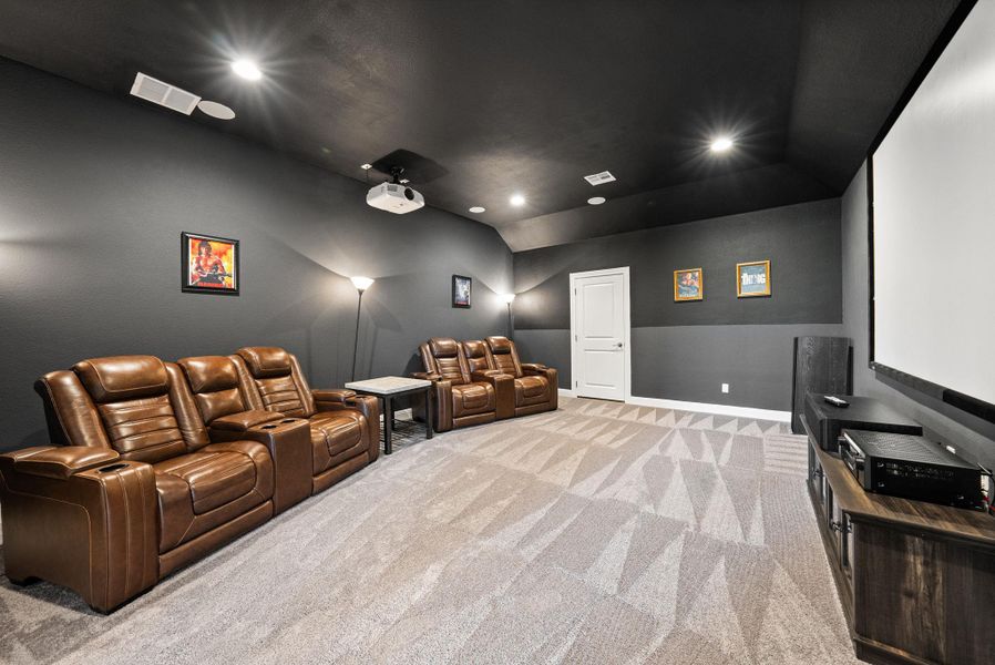 Home theater room with vaulted ceiling, recessed lighting, and light carpet