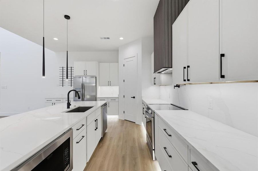 Kitchen featuring white cabinetry, stainless steel appliances, light wood-style flooring, and recessed lighting Kitchen featuring white cabinetry, stainless steel appliances, light wood-style flooring, and recessed lighting