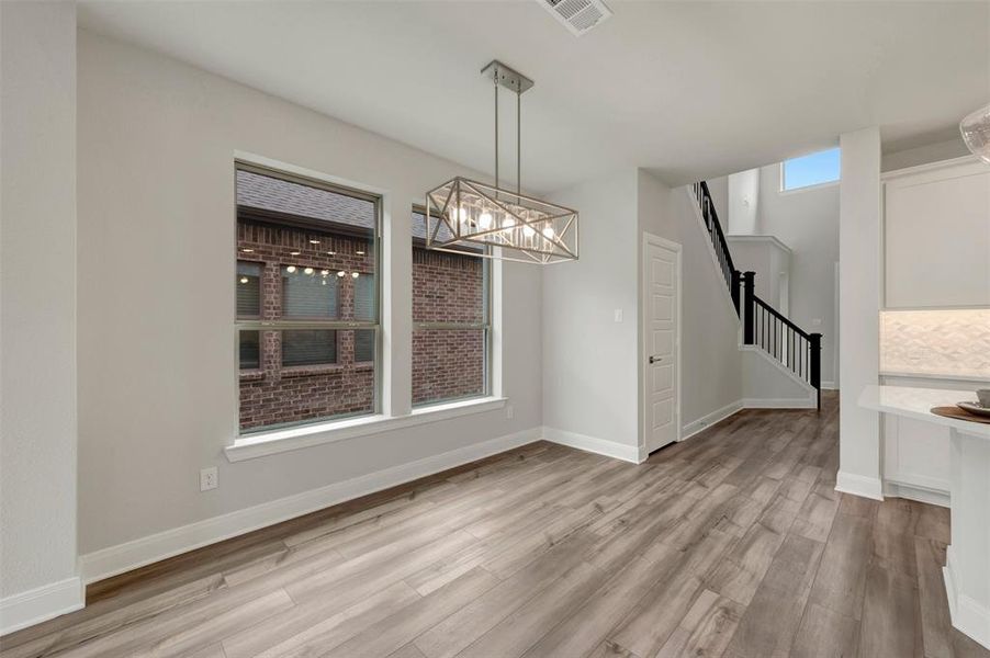 Open concept dining area featuring wood-finish flooring, a modern linear chandelier, and two large windows