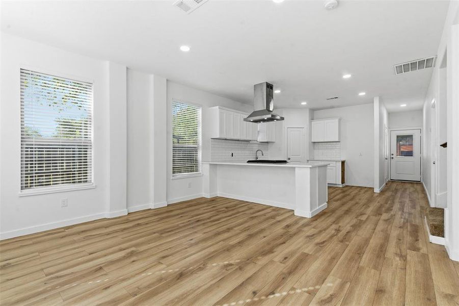 Kitchen with a peninsula, decorative backsplash, light countertops, white cabinetry, and open floor plan Kitchen with a peninsula, decorative backsplash, light countertops, white cabinetry, and open floor plan