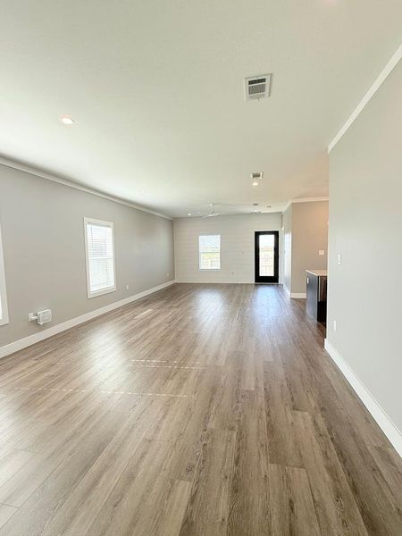 A generously proportioned living area features durable wood-look flooring and multiple windows for abundant illumination.