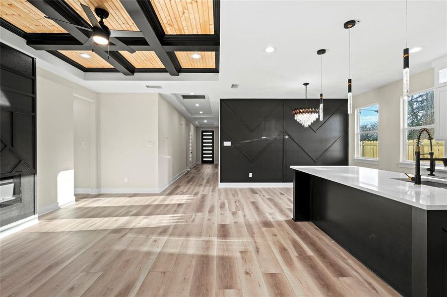 Kitchen featuring sink, coffered ceiling, beamed ceiling, decorative light fixtures, and light wood-type flooring