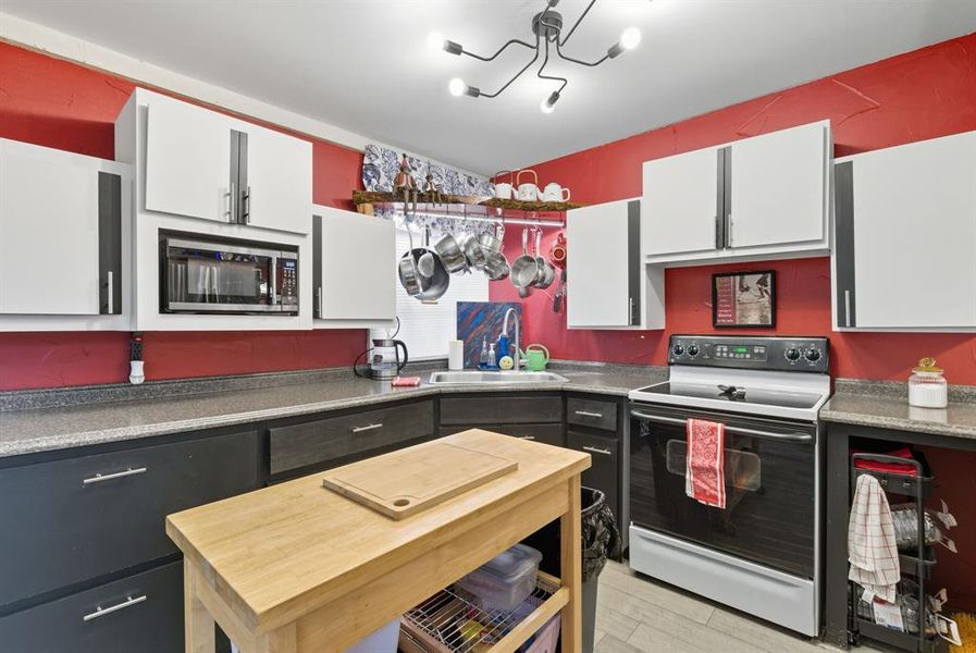 Kitchen featuring electric stove, white cabinets, dark countertops, and stainless steel microwave Kitchen featuring electric stove, white cabinets, dark countertops, and stainless steel microwave