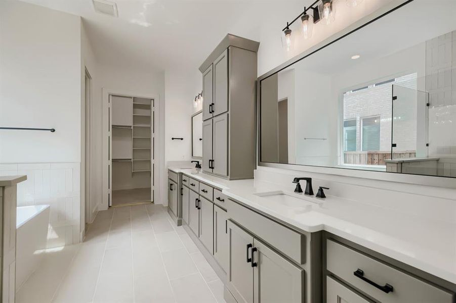 Bathroom featuring dual vanities with light gray cabinetry and white countertops Bathroom featuring dual vanities with light gray cabinetry and white countertops