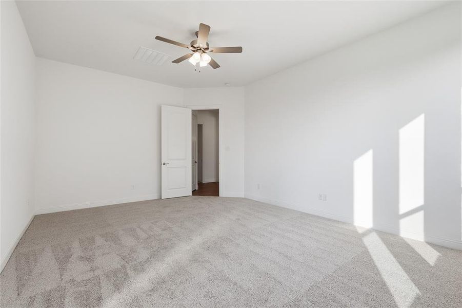 Empty room with light carpet and a ceiling fan