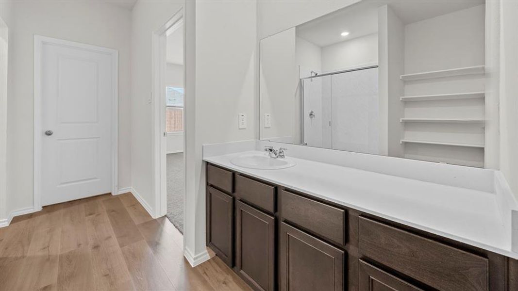 Full bath featuring a shower stall, vanity, and light wood finished floors