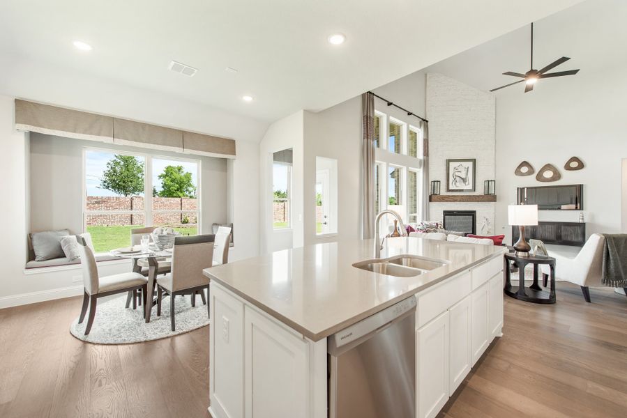 Open-concept kitchen with white island, sink, and views of dining area and living room with fireplace Open-concept kitchen with white island, sink, and views of dining area and living room with fireplace