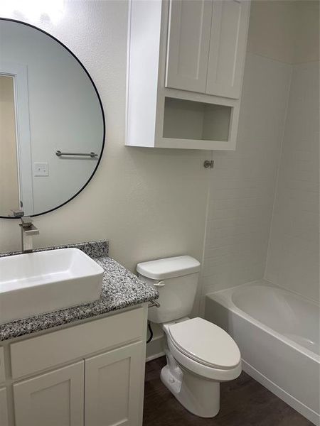 Full bathroom featuring hardwood / wood-style floors, shower / bath combination, vanity, and toilet