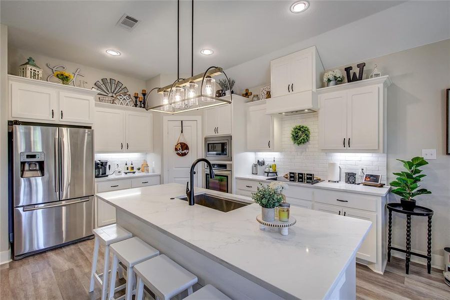 Kitchen featuring white cabinets, an island with sink, and appliances with stainless steel finishes