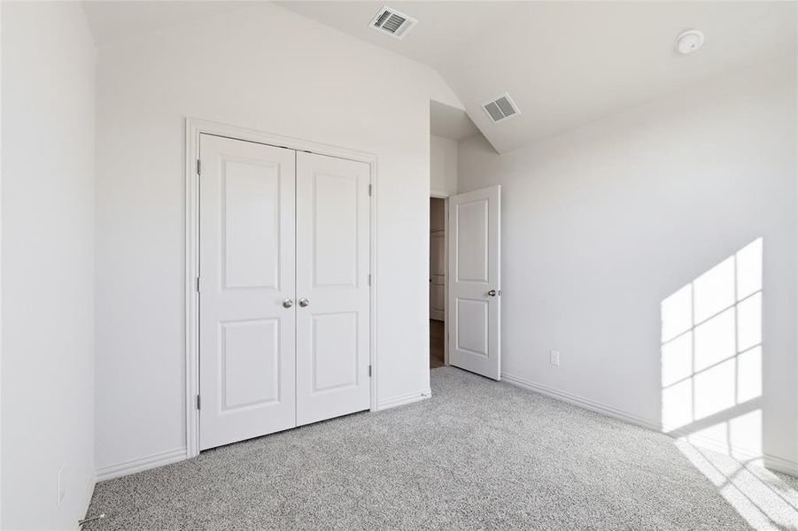 Unfurnished bedroom with lofted ceiling, light colored carpet, and a closet Unfurnished bedroom with lofted ceiling, light colored carpet, and a closet