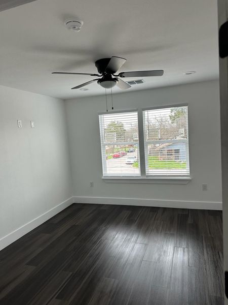 Unfurnished room featuring dark wood-style flooring and ceiling fan Unfurnished room featuring dark wood-style flooring and ceiling fan