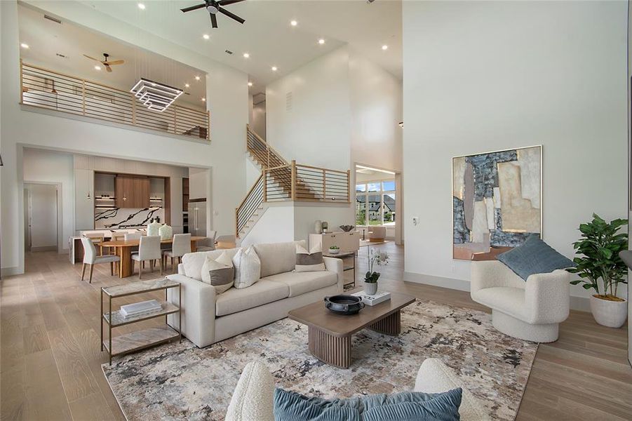 Living area featuring a towering ceiling, ceiling fan, wood finished floors, stairs, and recessed lighting