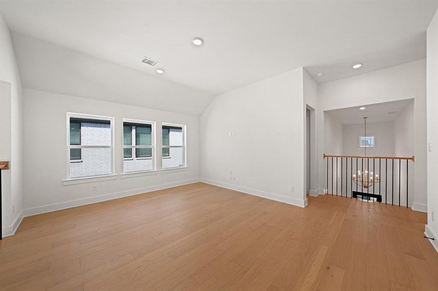 Unfurnished room with light wood finished floors, recessed lighting, lofted ceiling, and a chandelier Unfurnished room with light wood finished floors, recessed lighting, lofted ceiling, and a chandelier