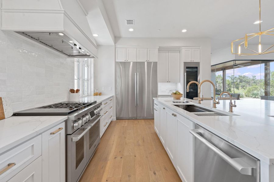 Kitchen featuring decorative backsplash, recessed lighting, custom range hood, a sink, and premium appliances Kitchen featuring decorative backsplash, recessed lighting, custom range hood, a sink, and premium appliances