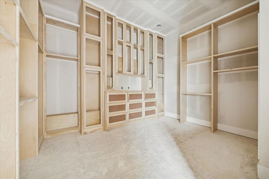 Boutique-style primary closet featuring soaring high ceilings and extensive custom built-in shelving. This massive walk-in dressing room offers an abundance of storage with tailored compartments, hanging rods, and sleek modern lines. The expansive layout and premium craftsmanship provide a highly organized, luxury storage solution that perfectly complements the sophisticated design of the primary suite. Boutique-style primary closet featuring soaring high ceilings and extensive custom built-in shelving. This massive walk-in dressing room offers an abundance of storage with tailored compartments, hanging rods, and sleek modern lines. The expansive layout and premium craftsmanship provide a highly organized, luxury storage solution that perfectly complements the sophisticated design of the primary suite.