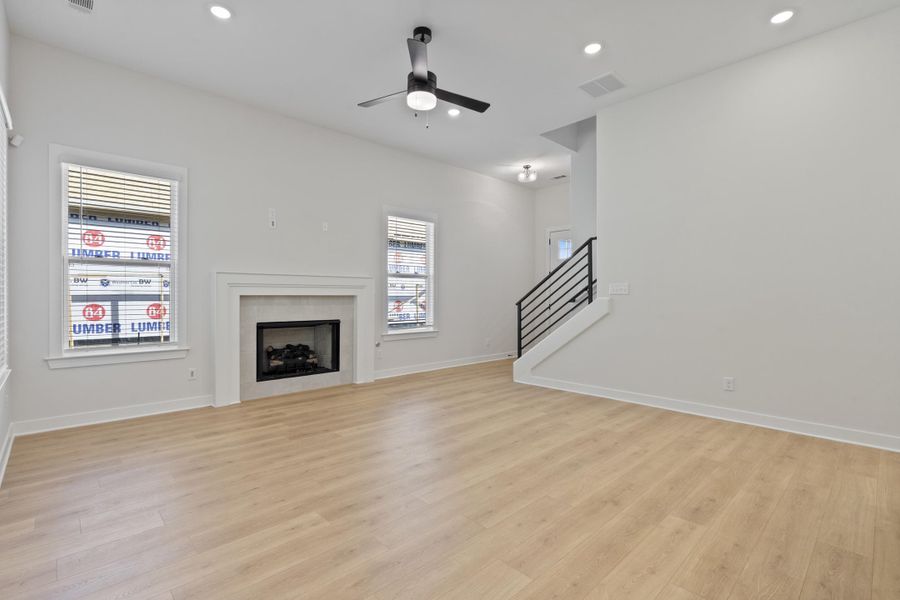 Vaulted ceiling, recessed lighting, wood-finish flooring, fireplace with mantel, and contemporary stair railing