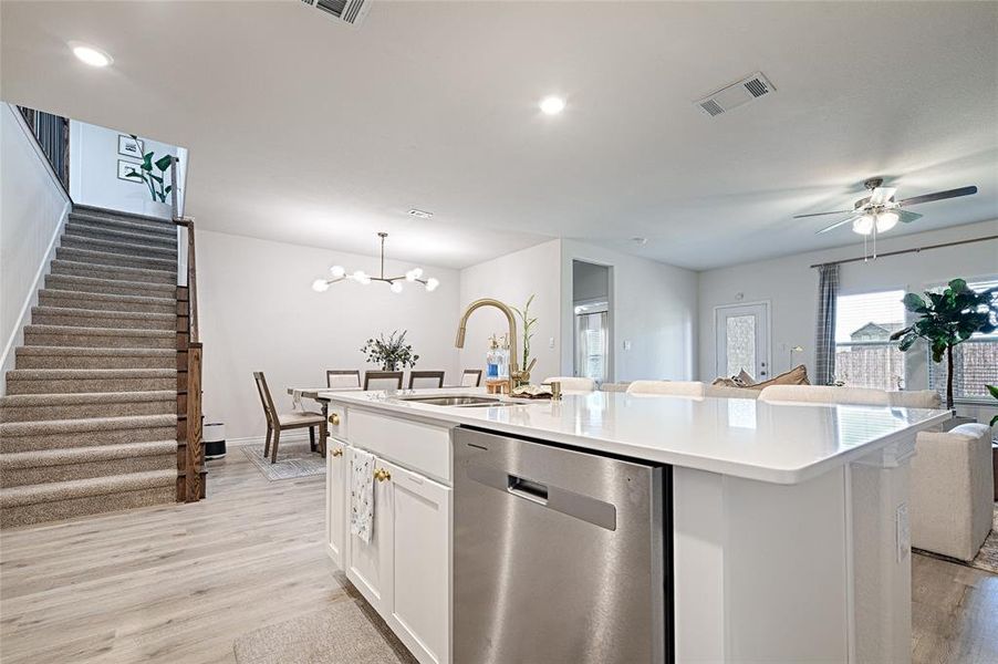 Kitchen with a center island with sink, sink, light hardwood / wood-style floors, white cabinetry, and dishwasher