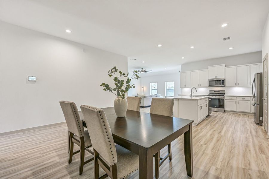 From the dining area, enjoy wide-open sightlines into the kitchen and family room. Recessed lighting and continuous wood-look flooring enhance the bright, airy feel of this thoughtfully designed open floor plan. From the dining area, enjoy wide-open sightlines into the kitchen and family room. Recessed lighting and continuous wood-look flooring enhance the bright, airy feel of this thoughtfully designed open floor plan.