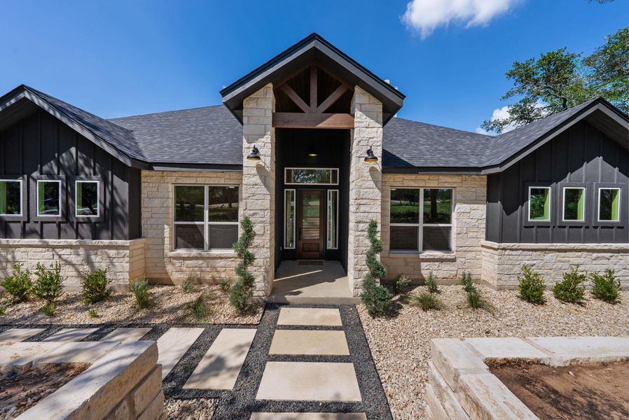 A striking contemporary residence boasts a stone and board-and-batten facade with a welcoming covered entry.