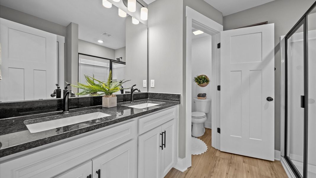 Notable primary bath featuring dual vanity, walk-in shower, and tasteful design touches throughout