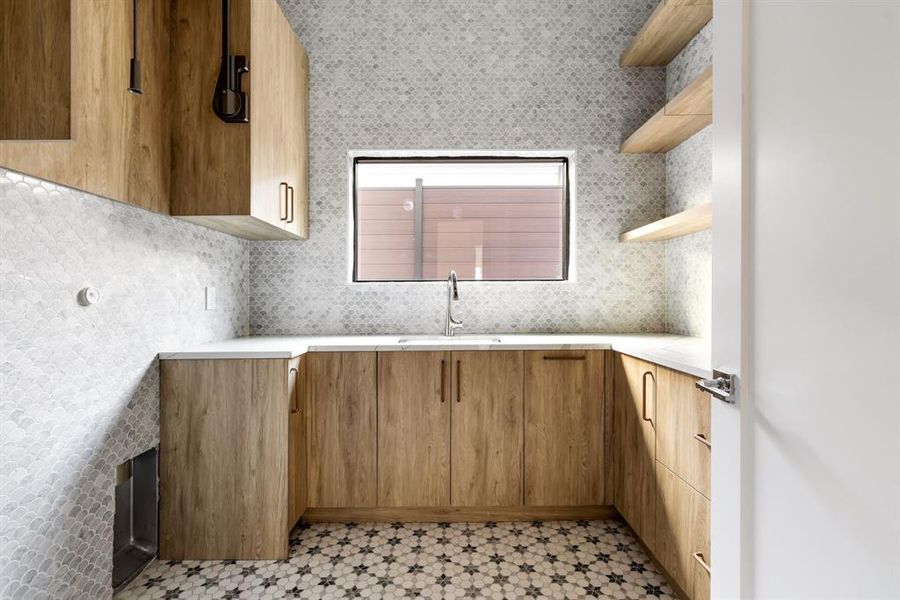 Kitchen featuring modern cabinets, open shelves, and light stone counters Kitchen featuring modern cabinets, open shelves, and light stone counters