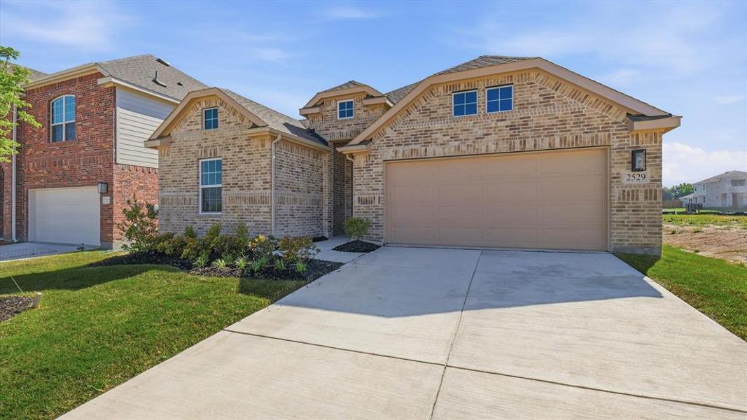 Light brick exterior with contrasting dark trim, featuring a two-car garage