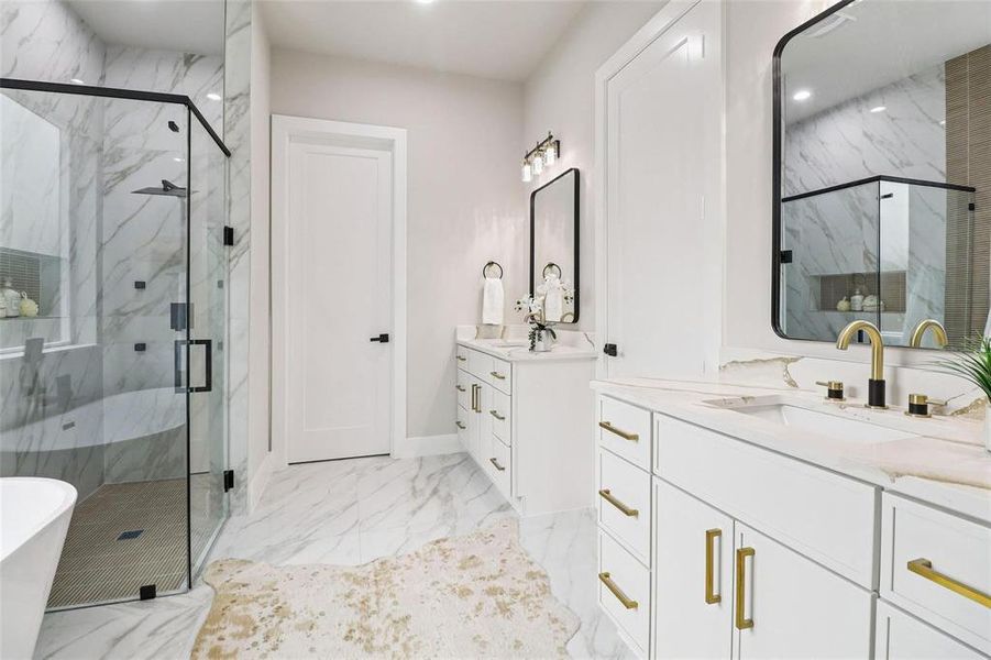 Spacious bathroom featuring a frameless glass shower enclosure with matte black hardware, dual white vanities with gold-tone fixtures, marble-patterned floor and wall tile, and built-in shower shelving