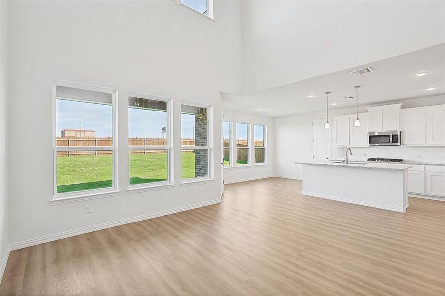 Unfurnished living room featuring sink, a high ceiling, and light wood-type flooring