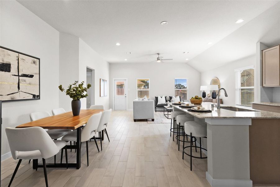 Open-concept kitchen, dining, and living area creates a bright, connected gathering space with a large island, bar seating, vaulted ceiling, and abundant natural light. Open-concept kitchen, dining, and living area creates a bright, connected gathering space with a large island, bar seating, vaulted ceiling, and abundant natural light.