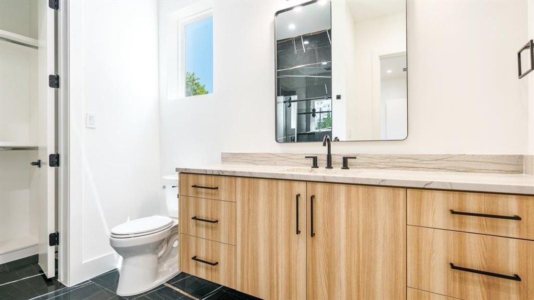 Bathroom featuring vanity, toilet, a healthy amount of sunlight, and tile patterned flooring