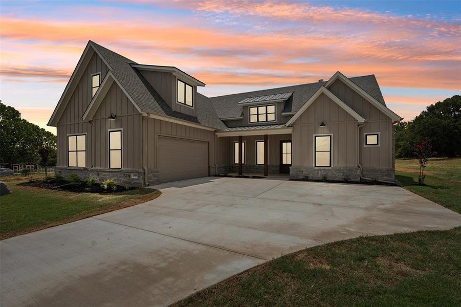 Modern farmhouse style home featuring a garage and a yard