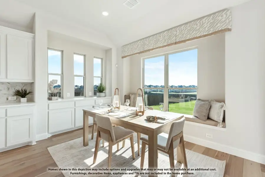 Bright dining area with wood table, built-in window seat, and hardwood floors next to white kitchen cabinets Bright dining area with wood table, built-in window seat, and hardwood floors next to white kitchen cabinets
