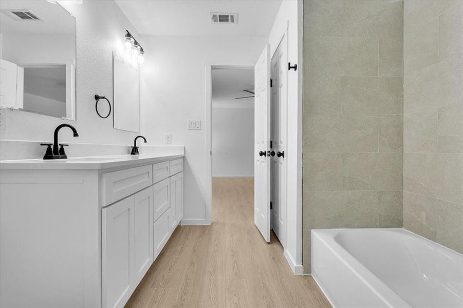 Bathroom with a tub, vanity, and wood-type flooring