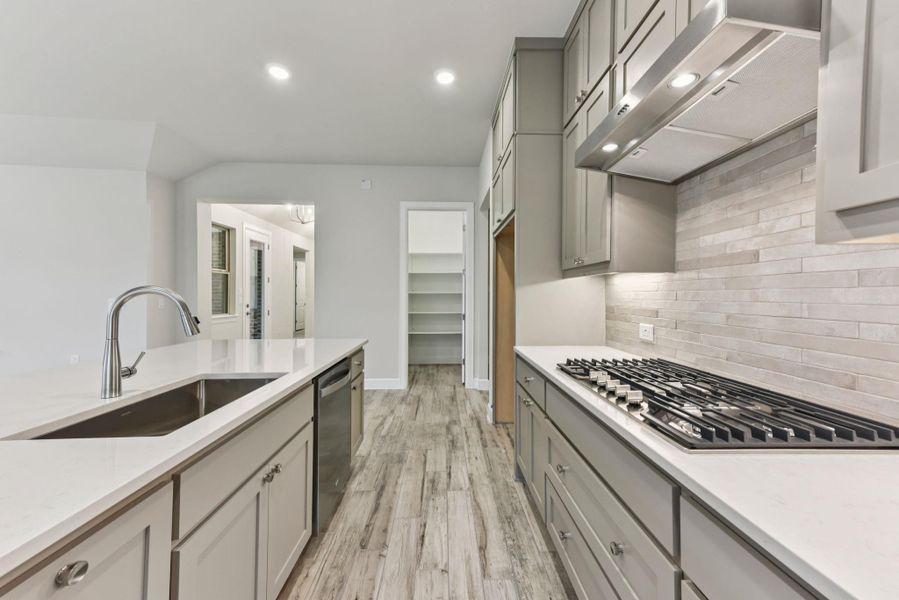 Kitchen featuring ventilation hood, light stone countertops, gray cabinets, stainless steel appliances, and light wood-type flooring