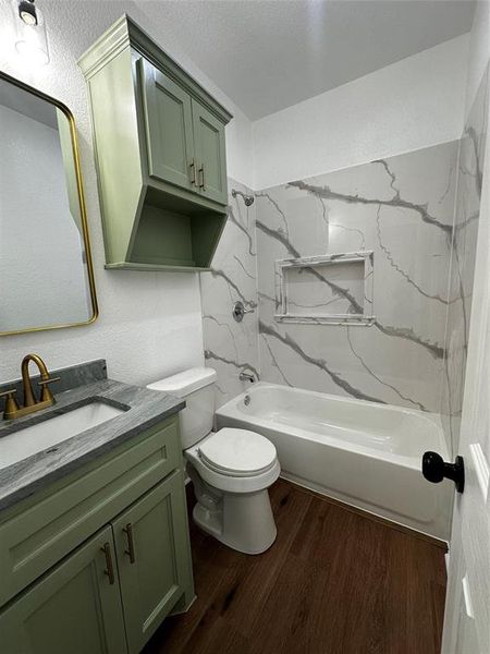 Bathroom featuring a vanity with a green cabinet, gray countertop, and brass-finish faucet