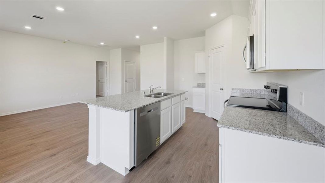Kitchen featuring light stone countertops, stainless steel appliances, white cabinetry, a kitchen island with sink, and dark wood-style flooring Kitchen featuring light stone countertops, stainless steel appliances, white cabinetry, a kitchen island with sink, and dark wood-style flooring