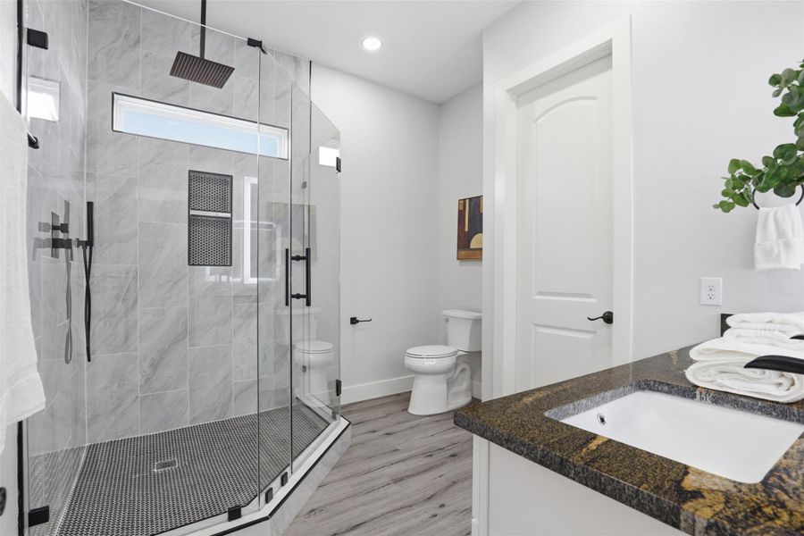Modern bathroom featuring a glass-enclosed shower with matte black fixtures, an overhead rain shower, and a built-in shower niche
